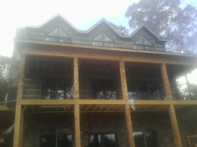Dormers and porch framing on a large log home under construction — Roof Coating work by our crew in Palacios
