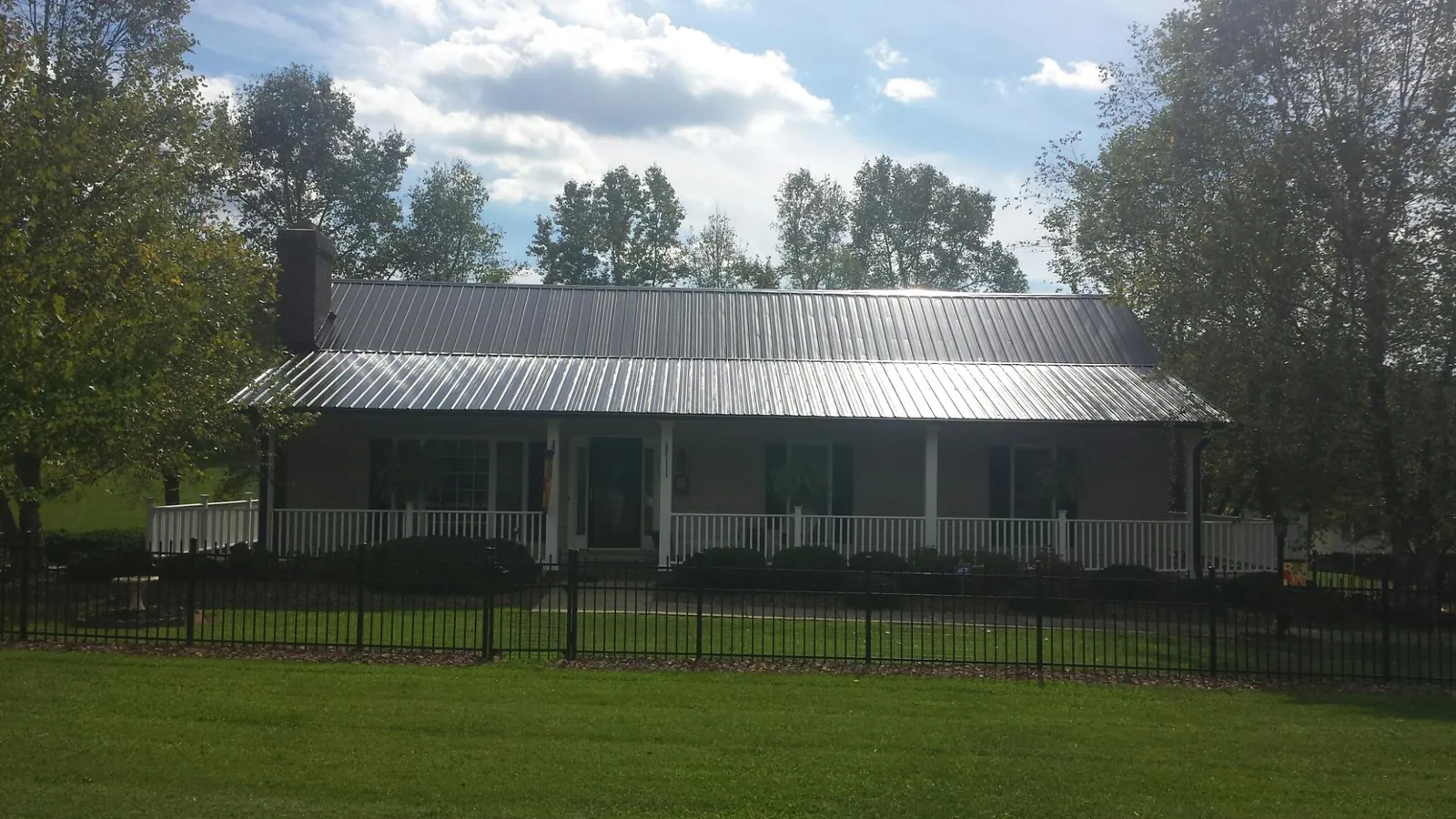 Gray metal roof on a brick ranch with a full width front porch — Gutter Guard Installation work by our crew in Palacios