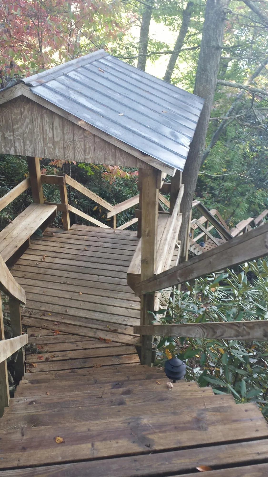 Metal roofed shelter over wooden steps on a wooded walkway — Skylight Repair & Installation work by our crew in Palacios
