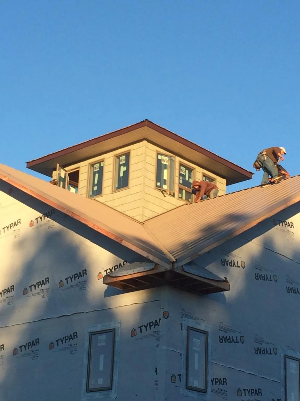 Roofers working around a rooftop cupola on a new metal roof at sunset — Roof Waterproofing in Palacios by Roofing Brothers